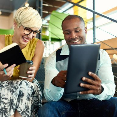 Team of young casual business people collaborating on an online project using a digital touchpad tablet computer in a bright modern office space. Serie with light flares